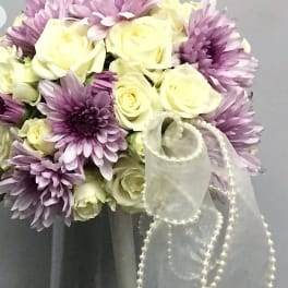 Bouquet of cream roses and lavender chrysanthemums in a glass vase with a sheer ribbon