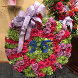 Round floral wreath with pink and lavender roses and a silver bow