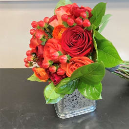 Bouquet of red and orange roses in a square glass vase