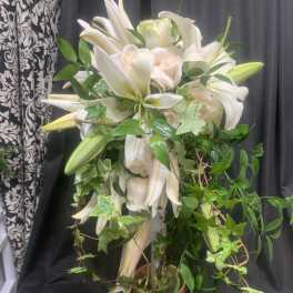 White lilies and pale roses in a copper vase with trailing ivy