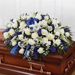 White and blue floral spray on a wooden casket