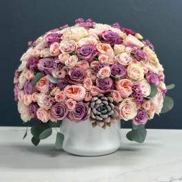 Round bouquet of pink and purple roses in a white vase