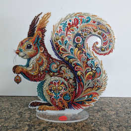 Colorful jeweled squirrel figurine with intricate paisley patterns on a clear stand