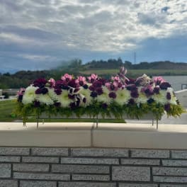 Long floral centerpiece with white and purple blooms on a metal stand