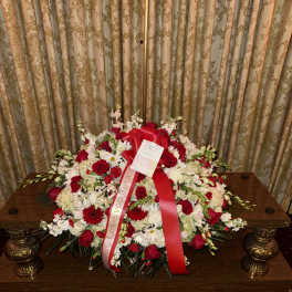 Large red and white floral spray with ribbon on a table