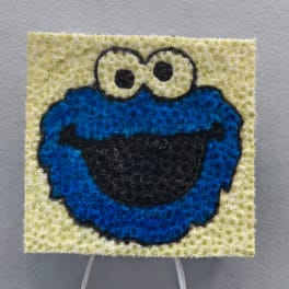 Cookie Monster floral tribute on a stand with white ribbon bows