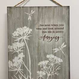 Rustic wood wall sign with white floral silhouettes, dragonflies, and an inspirational quote.