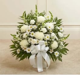 White floral arrangement in a white container with a ribbon bow
