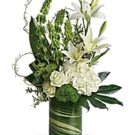 White lilies and roses arranged in a green glass vase