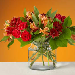 Bouquet of red roses and orange alstroemeria in a clear glass vase