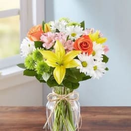 Mixed bouquet of lilies, roses, and daisies in a glass vase