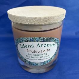 Tan soy candle in a glass jar with light wooden lid and decorative label on a blue background