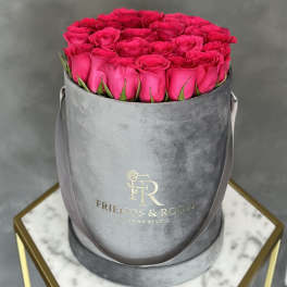 Hot pink roses arranged in a gray round hat box