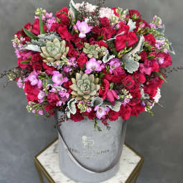 Large bouquet of red and pink roses with succulents in a gray hatbox