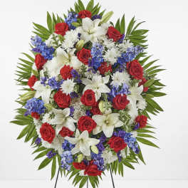 Standing floral spray with red roses, white lilies, and blue flowers