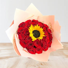 Bouquet of red roses with a sunflower center wrapped in peach paper