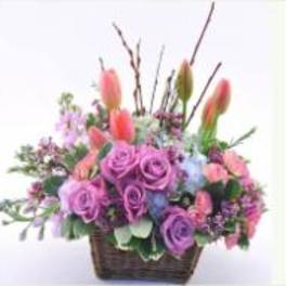 Basket arrangement of pink and purple flowers with tall tulips