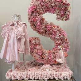 Pink floral number display with a baby dress and gift items