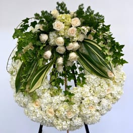 Large white floral wreath with roses and hydrangeas on an easel