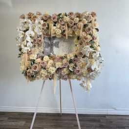Floral standing easel with white orchids and blush roses around a framed tribute