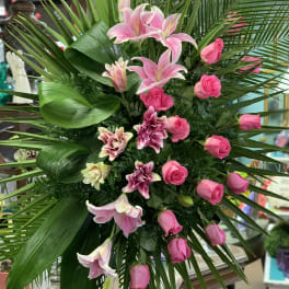 Tall pink lily and rose arrangement with palm fronds