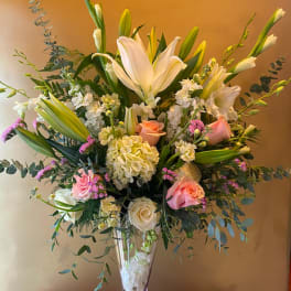 Tall bouquet of white lilies and pink roses in a clear glass vase