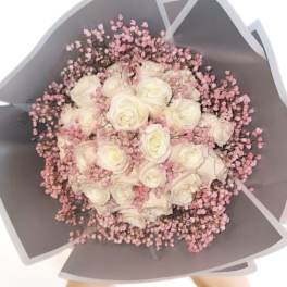 Bouquet of white roses with pink filler flowers in gray wrapping
