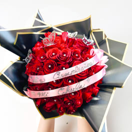 Bouquet of red roses wrapped in black paper with pink ribbon