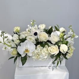 White floral arrangement with roses and orchids in a rectangular box
