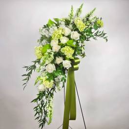 White roses and green flowers arranged on a standing easel with a ribbon
