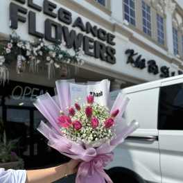 Pink tulip bouquet wrapped in lavender paper with baby's breath