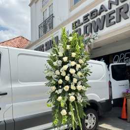 Tall standing floral spray with white roses and greenery on a metal easel