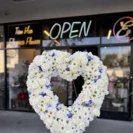 Heart-shaped floral wreath of white roses and daisies with blue accents