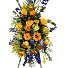 Tall standing floral spray with yellow and orange flowers and blue accents
