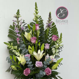 Tall arrangement of pink roses and white lilies in a white urn