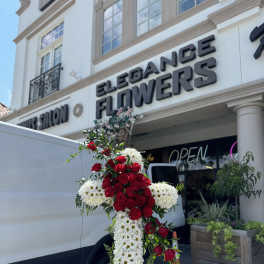 Standing floral cross of red roses and white daisies on an easel