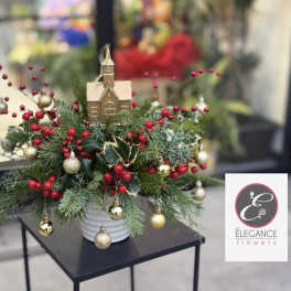 Christmas centerpiece with evergreen branches, red berries, and gold ornaments in a white vase