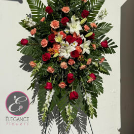 Standing floral spray with red roses, white lilies, and peach carnations