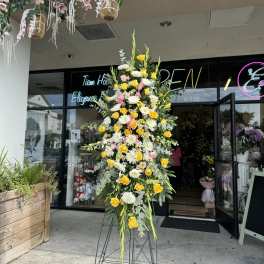 Tall standing floral spray with yellow and white blooms on a metal easel