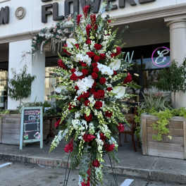 Tall standing floral spray with red and white flowers on a black easel