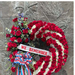 Large red and white rose wreath with a "WE REMEMBER" ribbon