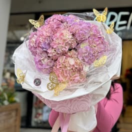 Large bouquet of pink and lavender hydrangeas wrapped in white paper