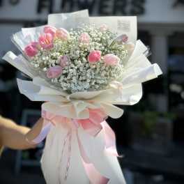 Pink tulip bouquet with baby's breath wrapped in white paper and ribbon