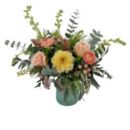 Mixed bouquet of peach and yellow flowers in a teal vase