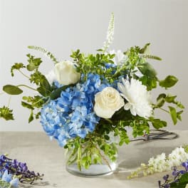 Blue hydrangeas and white roses in a clear glass vase