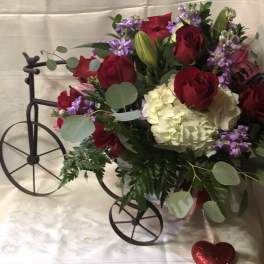 Bouquet of red roses, white hydrangea, and purple flowers in a decorative cart