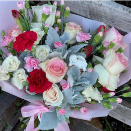 Bouquet of pink and white roses with red carnations and pale blue foliage