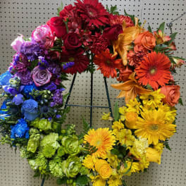 Rainbow-colored floral wreath with roses, gerbera daisies, and carnations