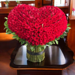 Heart-shaped bouquet of red roses with greenery at the base