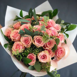 Bouquet of pink roses with white wrapping and greenery